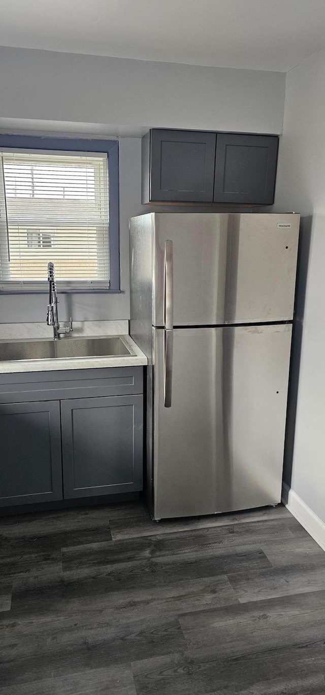 kitchen with freestanding refrigerator, dark wood finished floors, light countertops, a sink, and gray cabinetry