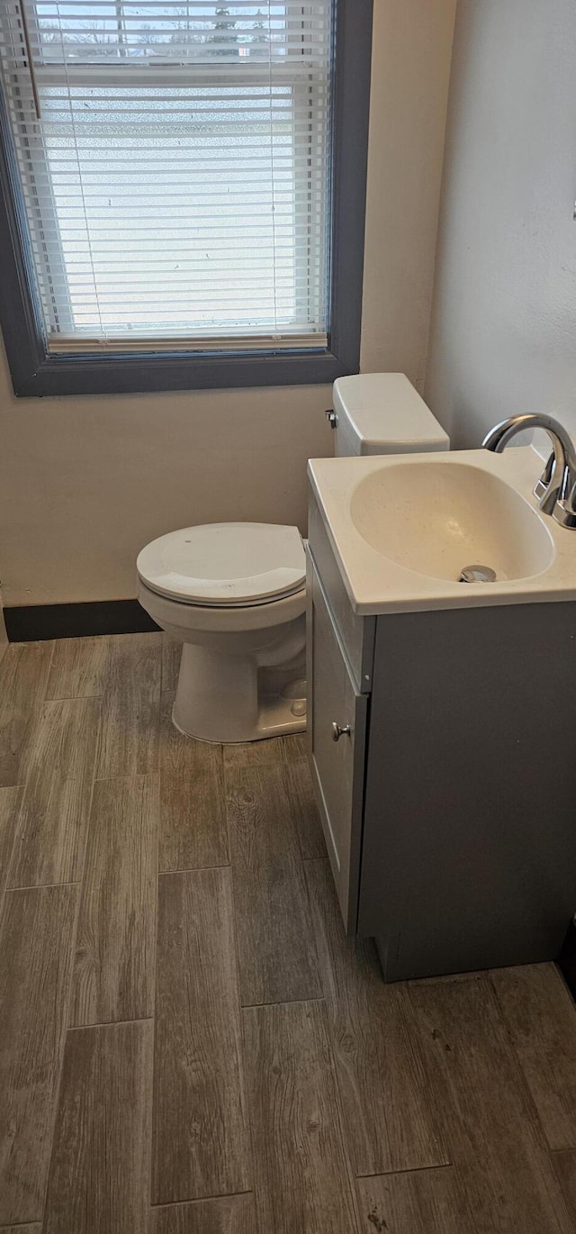 half bath featuring vanity, toilet, and wood finished floors