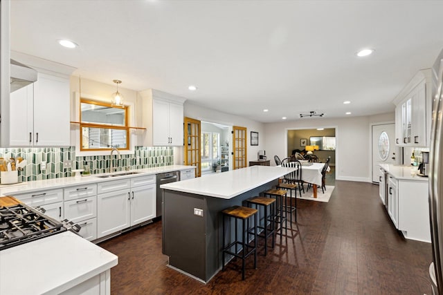 7101 River Glen Dr, Caledonia, MI 49316 - kitchen with a kitchen breakfast bar, a sink, a kitchen island, dark wood finished floors, and decorative backsplash