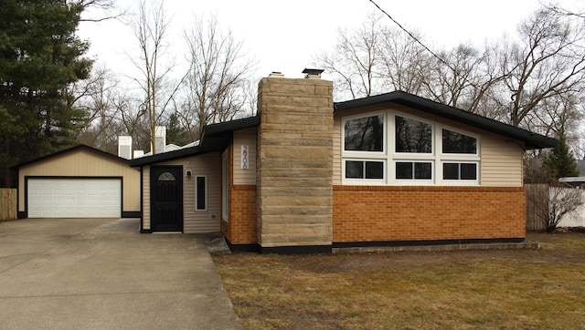 view of front of house with an attached garage, a chimney, driveway, and brick siding