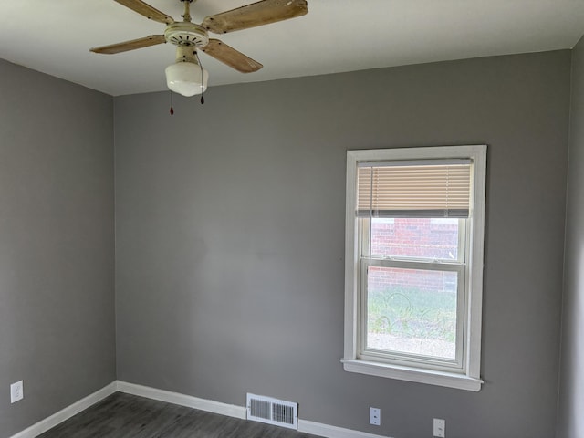 empty room with dark wood-type flooring, visible vents, baseboards, and a ceiling fan