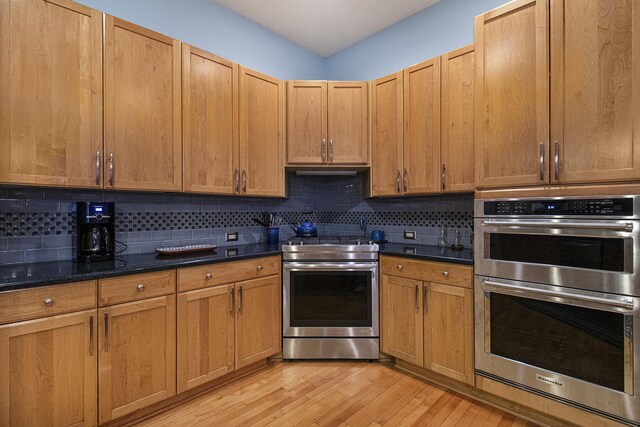 5002 Quincy Ct, Saline, MI 48176 - kitchen with appliances with stainless steel finishes, tasteful backsplash, light wood finished floors, and dark stone countertops