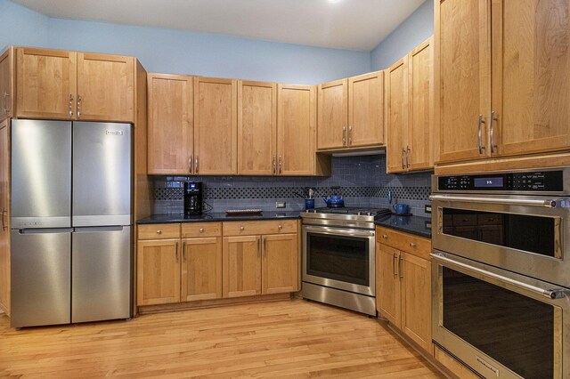 5002 Quincy Ct, Saline, MI 48176 - kitchen featuring stainless steel appliances, light wood-type flooring, tasteful backsplash, and dark countertops