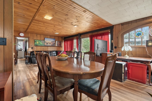dining space featuring a wealth of natural light, wooden walls, and light wood-type flooring
