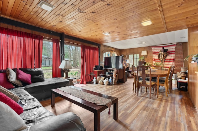 living room featuring wooden walls, light wood-type flooring, and wooden ceiling