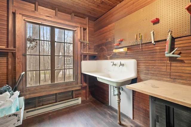 bar with a sink, wood ceiling, baseboard heating, wood finished floors, and wood walls