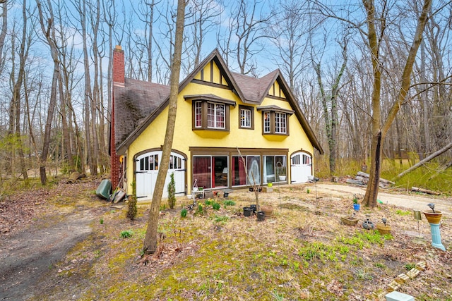view of front of home with roof with shingles, stucco siding, and a chimney