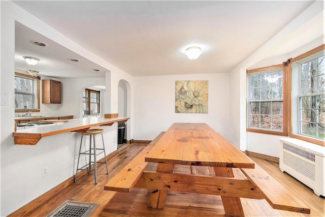 5353 Plum St, Coloma, MI 49038 - dining area with arched walkways, light wood-style flooring, and radiator heating unit