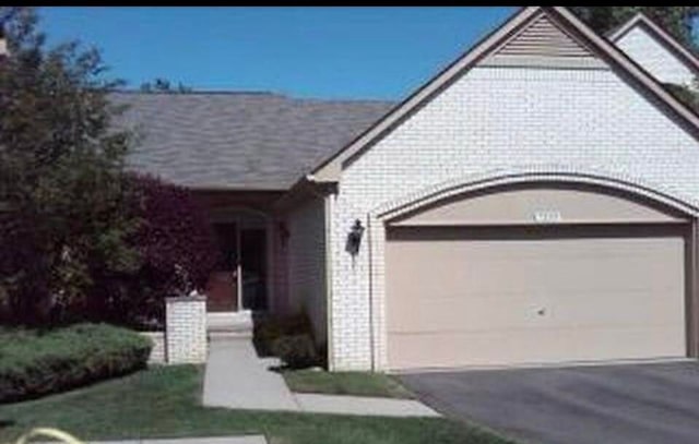 7355 Sherwood Crk, West Bloomfield, MI 48322 - view of front of property with a garage, driveway, and brick siding