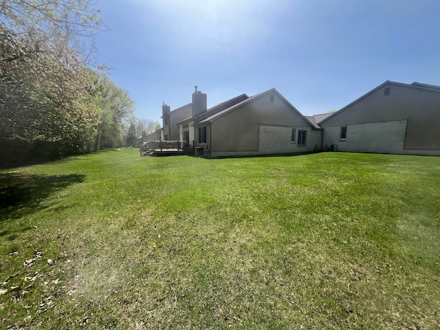 rear view of house with a yard, a chimney, and a wooden deck