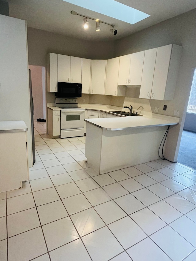 kitchen featuring black microwave, light countertops, track lighting, a peninsula, and white range with electric stovetop