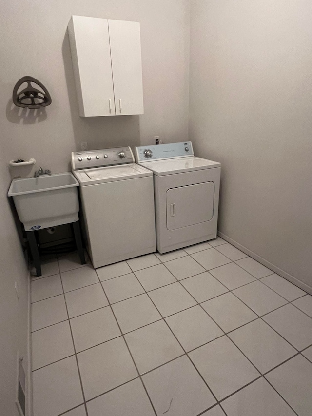 laundry area with cabinet space, light tile patterned flooring, a sink, visible vents, and washer and clothes dryer