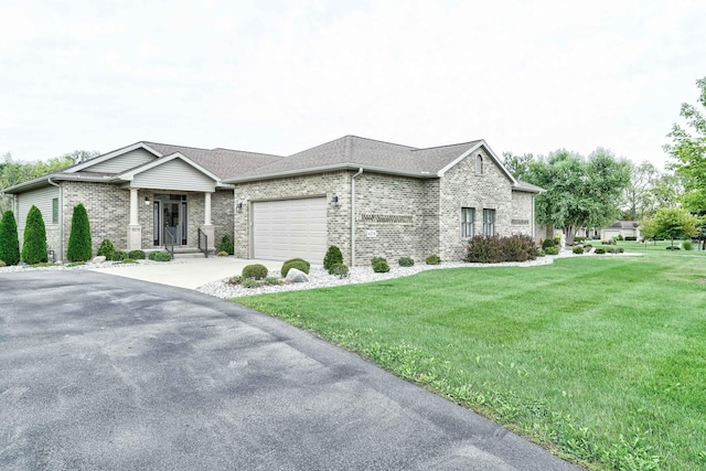 view of front of home with brick siding, a front yard, an attached garage, and driveway