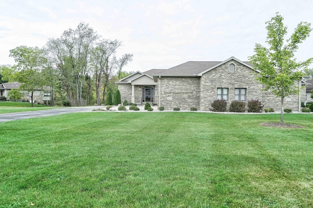 view of front of property featuring a front yard, brick siding, and driveway