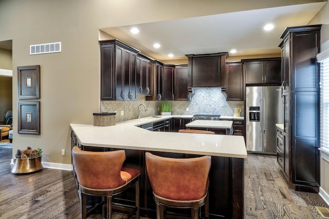 kitchen featuring visible vents, light countertops, dark brown cabinetry, high end fridge, and dark wood-type flooring