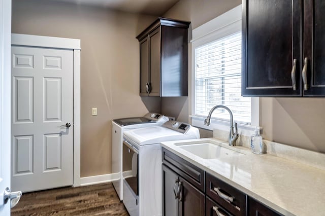 clothes washing area featuring dark wood-style flooring, baseboards, a sink, cabinet space, and washing machine and clothes dryer