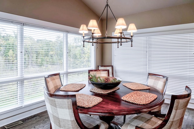 dining area with wood finished floors, a notable chandelier, vaulted ceiling, and visible vents