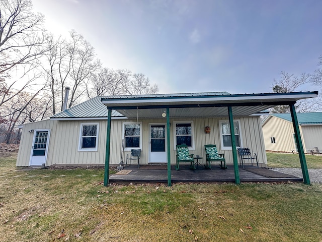 back of property with a porch, board and batten siding, metal roof, and a lawn