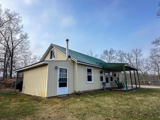 rear view of property featuring metal roof and a lawn