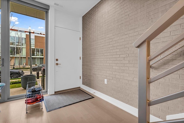 interior space with brick wall, plenty of natural light, and wood finished floors