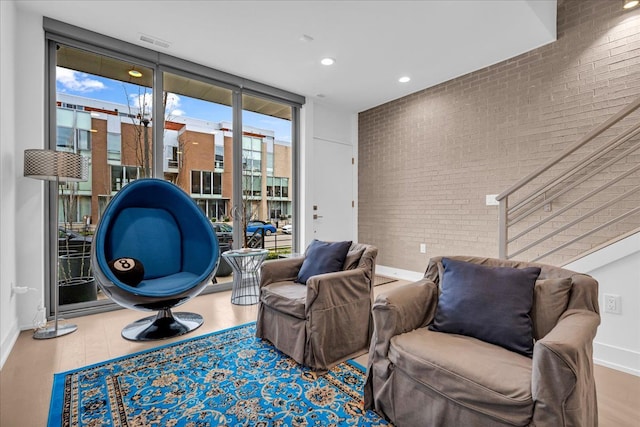 229 Alfred St, Detroit, MI 48201 - living area featuring brick wall, wood finished floors, baseboards, recessed lighting, and expansive windows