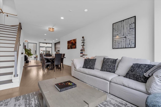 living room featuring wood finished floors, recessed lighting, and stairs