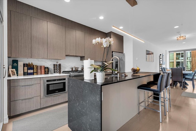 kitchen featuring a breakfast bar, recessed lighting, an island with sink, open floor plan, and modern cabinets