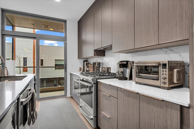 kitchen with light carpet, a toaster, modern cabinets, stainless steel appliances, and a sink