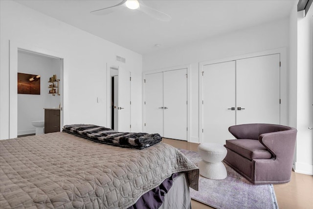 bedroom featuring visible vents, multiple closets, ceiling fan, and ensuite bath