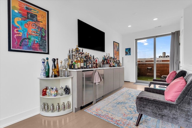 bar featuring freestanding refrigerator, a dry bar, recessed lighting, wood finished floors, and baseboards
