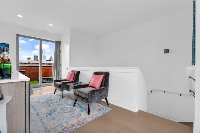 sitting room with wood finished floors, an upstairs landing, and recessed lighting