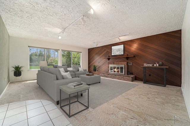 living room featuring a textured ceiling, a brick fireplace, wood walls, track lighting, and an accent wall