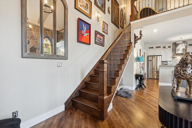stairway featuring baseboards, hardwood / wood-style flooring, and recessed lighting