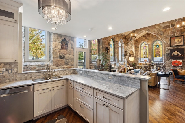 kitchen featuring stainless steel dishwasher, a sink, light stone countertops, open floor plan, and dark wood-style floors