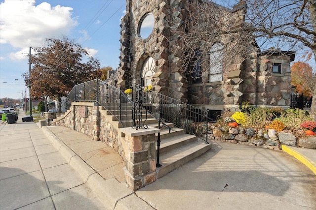 view of home's exterior with stairs and stone siding