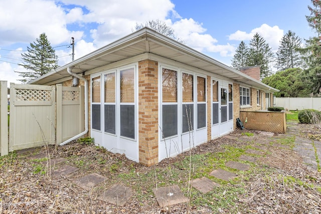 view of home's exterior featuring fence, a sunroom, and a chimney