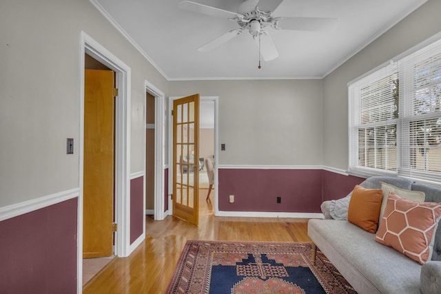 sitting room featuring a ceiling fan, wood finished floors, baseboards, and ornamental molding