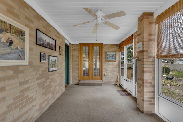 unfurnished sunroom with brick wall, french doors, a ceiling fan, and carpet floors