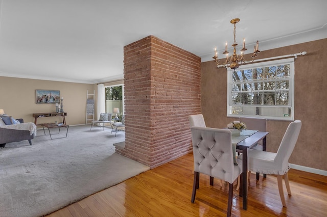 dining room with ornamental molding, baseboards, a chandelier, and wood finished floors