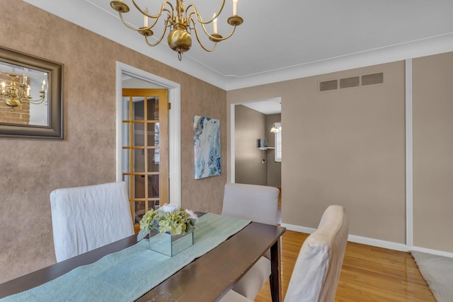 dining room featuring visible vents, baseboards, an inviting chandelier, and wood finished floors