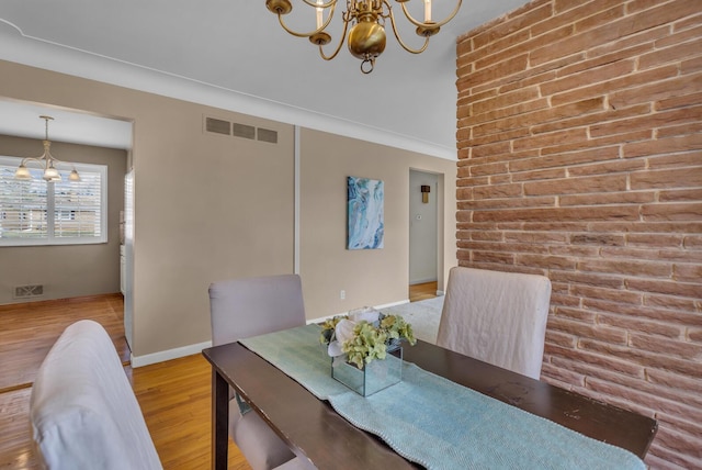 dining room featuring baseboards, wood finished floors, a notable chandelier, and visible vents