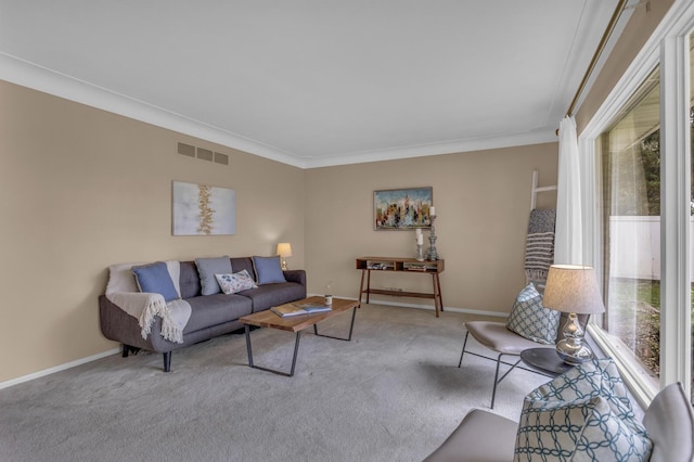 carpeted living room with plenty of natural light, visible vents, baseboards, and ornamental molding