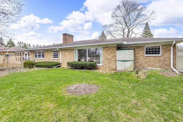 rear view of house with brick siding, a chimney, fence, and a lawn