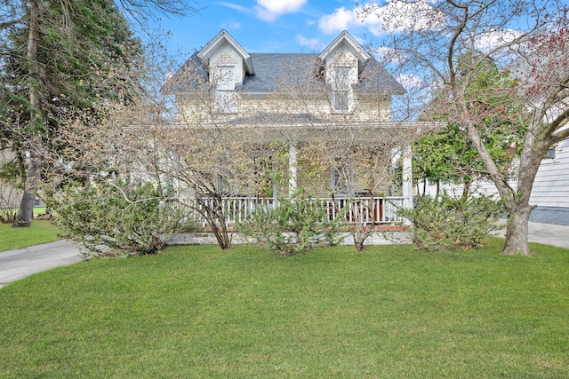 new england style home with a front yard and a shingled roof