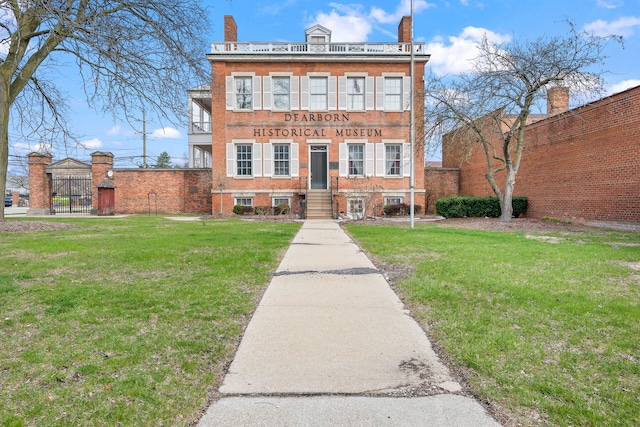 view of front facade with a chimney, fence, a front lawn, and brick siding