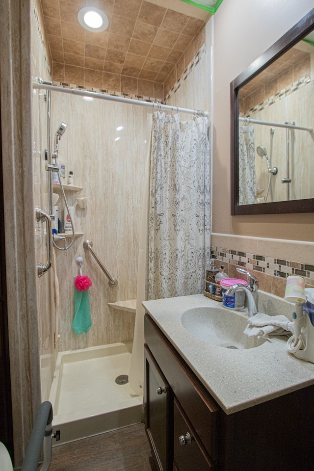 bathroom featuring a shower stall, vanity, and backsplash