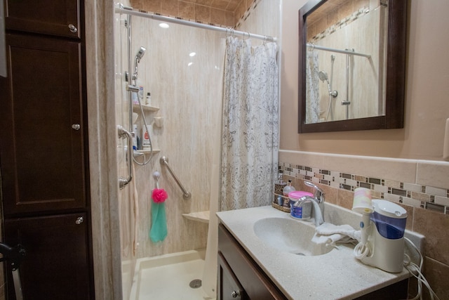 bathroom featuring a stall shower, vanity, and tile walls