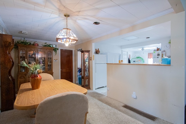 dining area featuring crown molding, visible vents, a chandelier, and light carpet