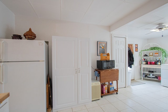 kitchen featuring washer / clothes dryer, black microwave, freestanding refrigerator, and ceiling fan