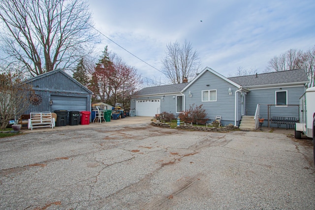 exterior space with an attached garage, a chimney, driveway, and an outdoor structure